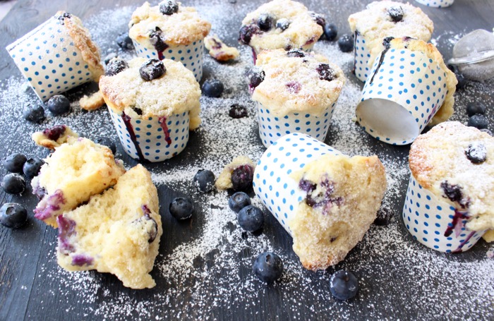 blueberry ricotta muffins in polka dot muffin cups on a wooden table