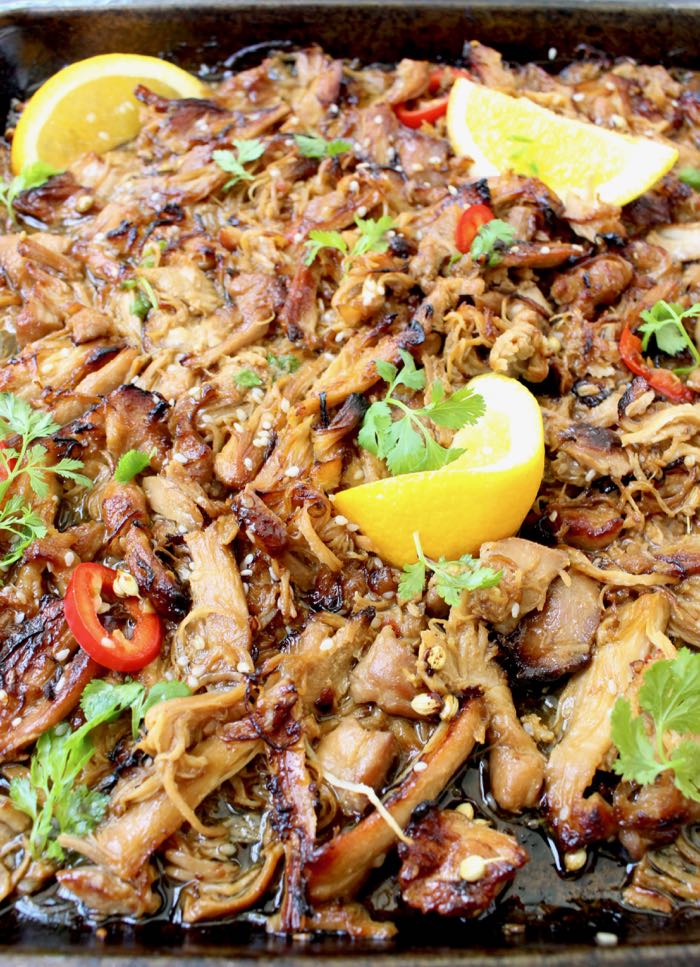 Tray of Asian style chicken carnitas with red chili and orange wedges 