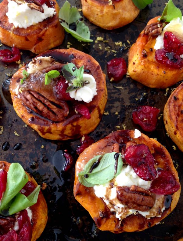 A Black Tray of Sweet Potato Appetizers, Topped with Goat Cheese, Candied Walnuts, Cranberries & Balsamic Glaze