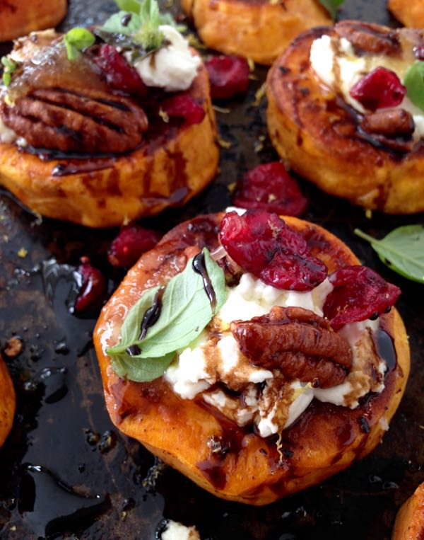 A Black Tray of Sweet Potato Appetizers Topped with Goat Cheese, Candied Walnuts, Cranberries & Balsamic Glaze