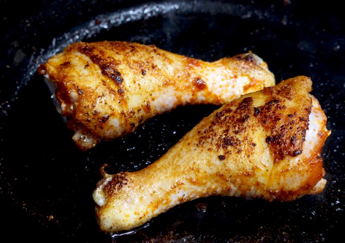 golden brown seared chicken legs in a black cast iron skillet