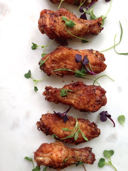 Baked Crispy Chicken Wings on a White Marble Sprinkled with Fresh Herbs