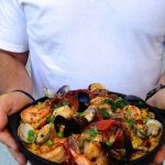 Man Holding a Pan of Seafood Paella