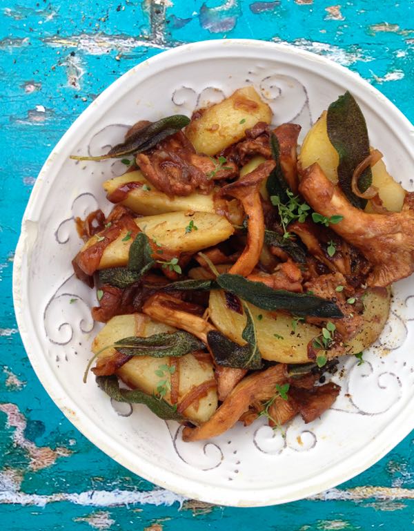 White Serving Bowl with Chanterelle Mushrooms and Crispy Sage Potatoes on a Blue Rustic Table