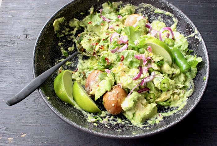 Black Rustic Bowl of Healthy Homemade Guacamole, with Limes and Red Onion
