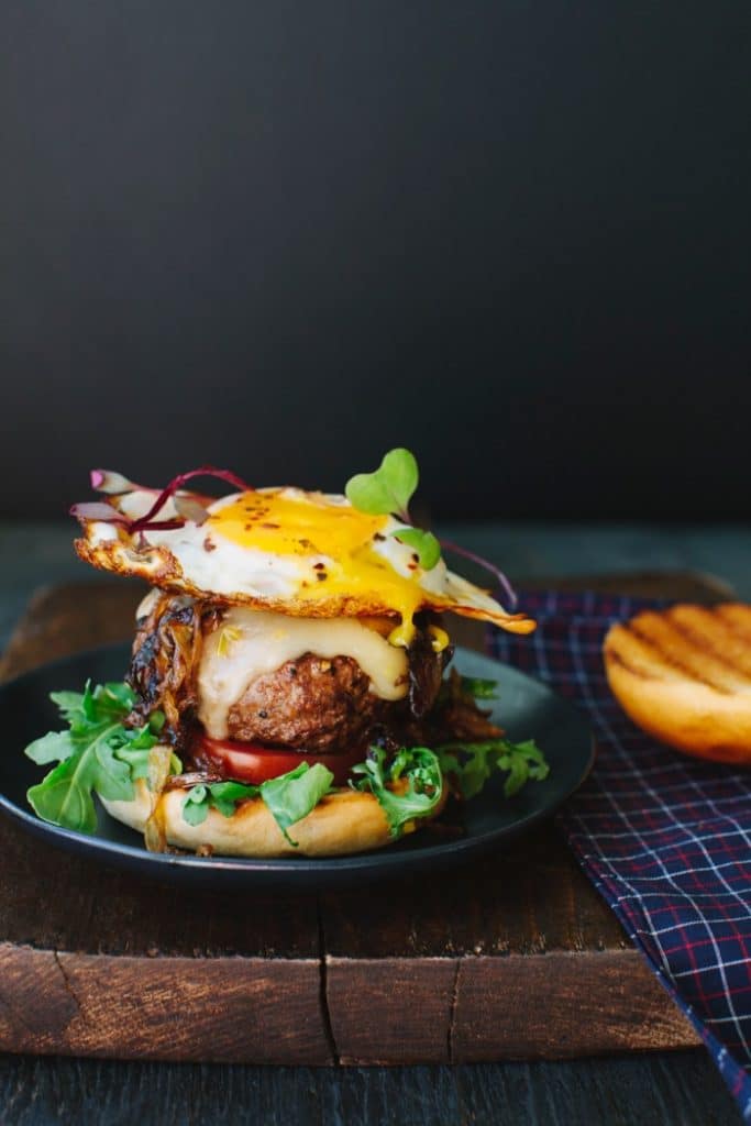 Image of Breakfast Egg Burger with Runny Yolk On a Wooden Board
