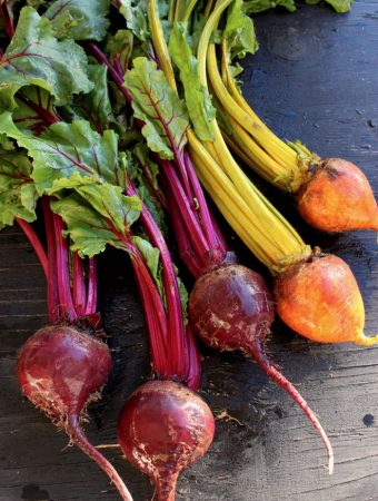 Bunch of Red and Golden Beets with Green Tops on Rustic Table