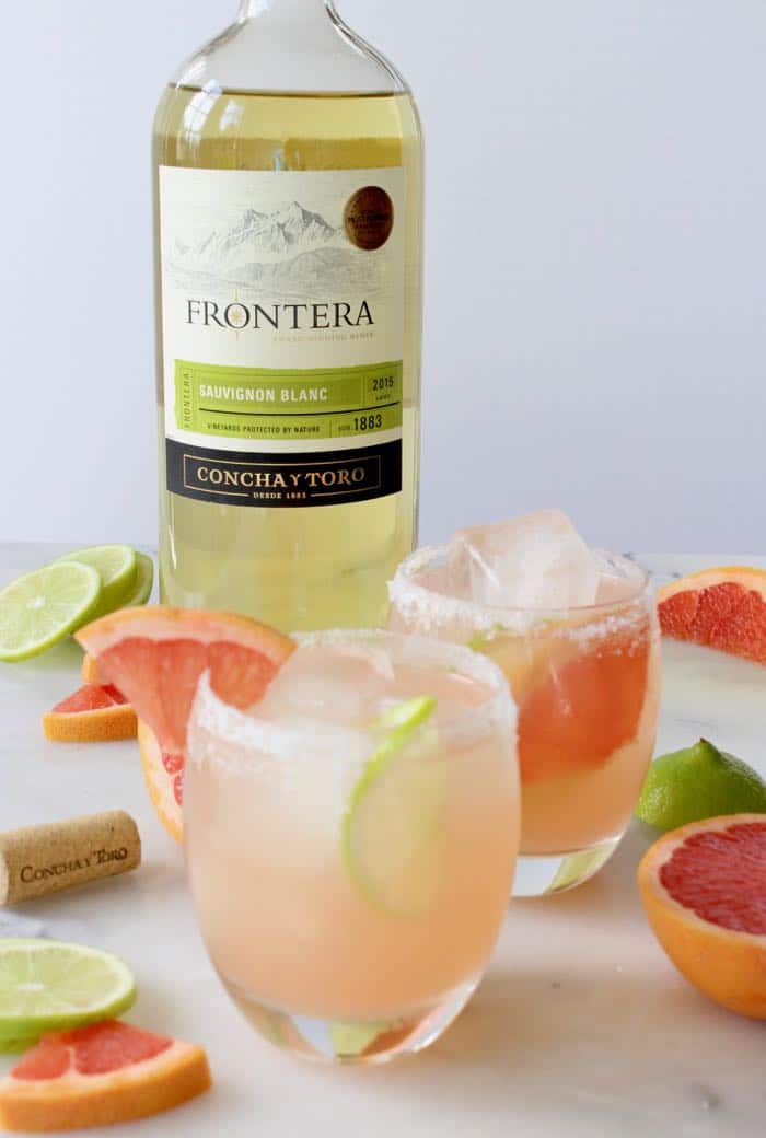 Glasses of Paloma cocktails on ice with sliced grapefruit and limes