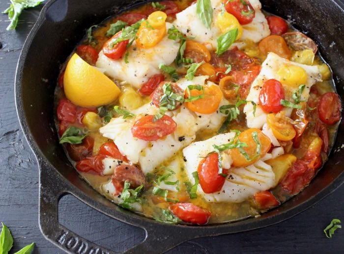 Pan Seared Halibut Fillets in Garlic White Wine Sauce with Heirloom Tomatoes and Basil in a Cast Iron Skillet